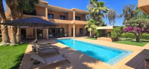 una villa con piscina con sombrilla y sillas en villa Bidouane, en Marrakech