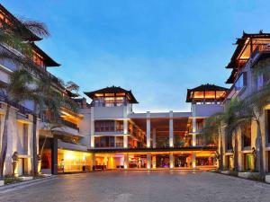 a large building with palm trees in front of it at Mercure Kuta Bali in Kuta