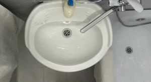 a white bathroom sink with a toothbrush in it at Minimalist 2-room Apartment in Aktobe +12 photos
