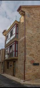 Un edificio alto de ladrillo con una ventana roja. en Apartamentos Praia do Capitàn, en Muxía
