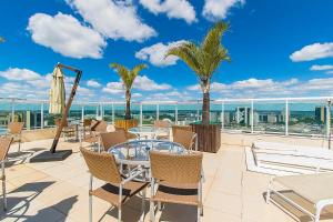 a patio with tables and chairs and palm trees at Saint Moritz Hotel em Brasília 63873 in Brasilia