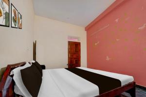 a bedroom with a bed and a red wall at Hotel O SNS Lodge Kallidaikurichchi in Tenkāsi