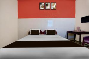 a bedroom with a bed with a red wall at Hotel O SNS Lodge Kallidaikurichchi in Tenkāsi