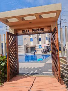 a wooden gate leading to a swimming pool with a building at apartamento frente a la playa condominio Data paraiso in Playas +4 photos
