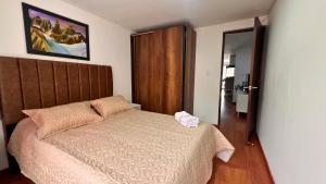 a bedroom with a bed with a wooden head board at Dúplex familiar cerca al Cable y Milán con patio in Manizales