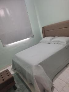 a bedroom with a white bed with a window at Lar Doce Lar in Itabira