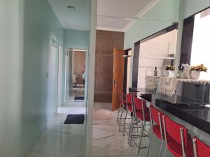 a kitchen with a counter with red chairs in it at Lar Doce Lar in Itabira