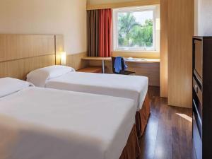a hotel room with two beds and a window at ibis Curitiba Aeroporto in São José dos Pinhais