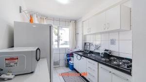 a kitchen with white cabinets and a white refrigerator at Apartamento em Sao Jose proximo a Arena Opus in Estêvão