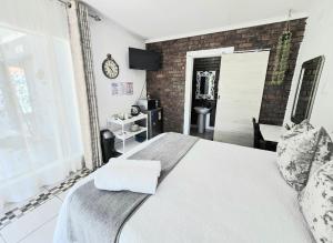 a bedroom with a white bed and a brick wall at Zhantique Guest House 1- Unit 2 in Boksburg +24 photos