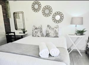 a bedroom with a white bed with pillows and a mirror at Zhantique Guest House 1- Unit 2 in Boksburg