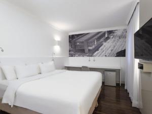 a white bedroom with a large bed and a tv at Mercure Sao Paulo Paulista in São Paulo