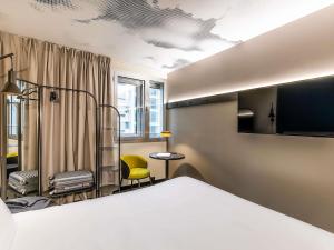 a bedroom with a bed and a yellow chair at Hotel ibis Lisboa Alfragide in Lisbon
