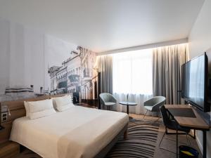 a hotel room with a bed and a desk and a television at Novotel Vilnius Centre in Vilnius +173 photos