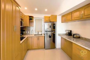 a kitchen with wooden cabinets and a stainless steel refrigerator at Beachfront Compound, Pool, BBQ, Best for Groups in Refugio +28 photos