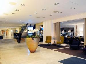 a lobby with a large vase with flowers in it at Pullman Eindhoven Cocagne in Eindhoven