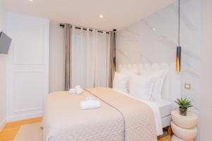a white bedroom with a large white bed with white pillows at Luxurious Apartment Stylish Design - René Boulanger in Paris
