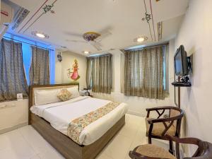 a bedroom with a bed and a tv and a chair at Storica Stays Panorama Haveli Udaipur in Udaipur