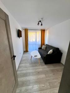 a living room with a black couch and a table at La Izvor Moinești, Cazare in Moineşti +12 photos