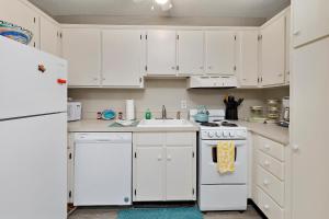 una cocina con armarios blancos y un horno de fogón blanco en Island Townhouse #E1, en East End