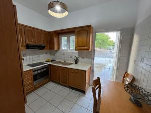 a kitchen with wooden cabinets and a table and a window at Eva's house in Rafina