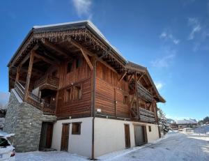 a large wooden building with snow on the ground at Le Cosy - Appartement in Les Gets