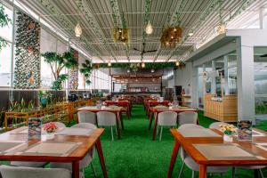 a restaurant with tables and chairs and green carpet at The Quadrant Hotel KNO in Medan
