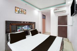 KaliānpurにあるSPOT ON New Shukla Hotelの白いベッドとテレビのある寝室
