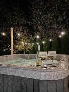 a hot tub with two wine glasses and a bottle of wine at Skandynawia in Uherce Mineralne