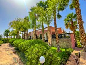 a house with palm trees in front of it at Nassau FarmHouse in Mellah Bakka