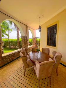 a dining room with a wooden table and chairs at Nassau FarmHouse in Mellah Bakka