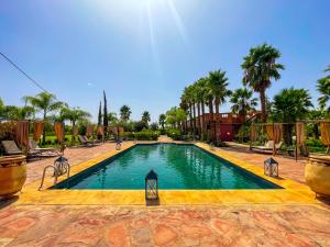 a swimming pool in a resort with palm trees at Nassau FarmHouse in Mellah Bakka