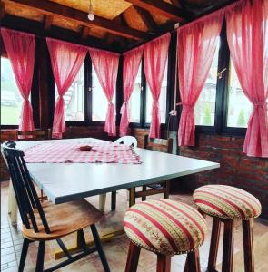 a dining room with a table and chairs with pink curtains at Apartmani Da-Da in Gornji Milanovac