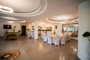 a banquet hall with white chairs and a table at Pensiunea Alexandra in Predeal