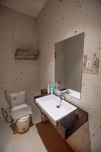 a bathroom with a sink and a toilet and a mirror at The Quadrant Hotel KNO in Medan