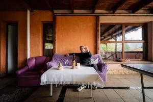 a man sitting on a purple couch with a bottle of wine at Pensiunea Alexandra in Predeal