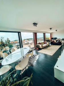 ヘールにあるPenthouse with spacious terraces in the heart of Geelのテーブルと椅子と大きな窓のあるリビングルーム