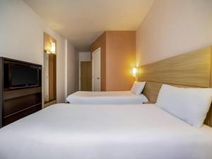 a hotel room with two beds and a flat screen tv at ibis Sao Paulo Interlagos in Sao Paulo +66 photos