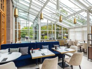 a restaurant with a blue couch and tables and chairs at PULLMAN Stuttgart Fontana in Stuttgart