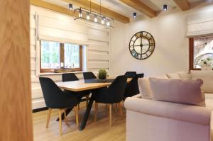 a dining room with a table and chairs and a couch at Forest Home Dębowa 18 in Łuka