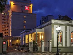 a building with a lit up sign next to a street light at ibis Curitiba Batel in Curitiba