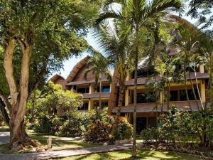 a building with palm trees in front of it at Mercure Resort Sanur in Sanur