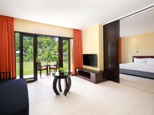a bedroom with a bed and a tv and a table at Mercure Resort Sanur in Sanur