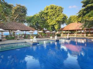 a swimming pool at a resort with tables and umbrellas at Mercure Resort Sanur in Sanur