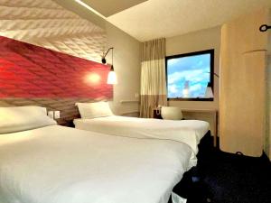 a hotel room with two beds and a flat screen tv at ibis Santos Gonzaga Praia in Santos