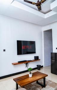 Una sala de estar con una mesa y un televisor en la pared. en Damian Luxury Homes, en Dar es Salaam
