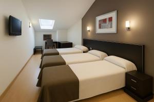 a room with four beds and a flat screen tv at Hotel Villa de Cacabelos in Cacabelos