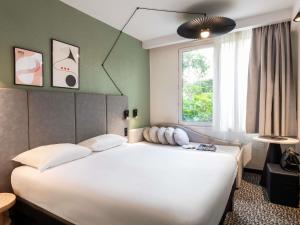Un dormitorio con una gran cama blanca con ventana. en ibis Paris Avenue d'Italie 13ème, en París 111 fotos más