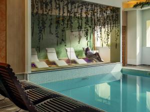 a swimming pool with chairs and a table and a swimming pool at Novotel Bucharest City Centre in Bucharest