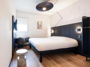 a bedroom with a large white bed and a desk at ibis Perpignan Sud Saint Charles in Perpignan